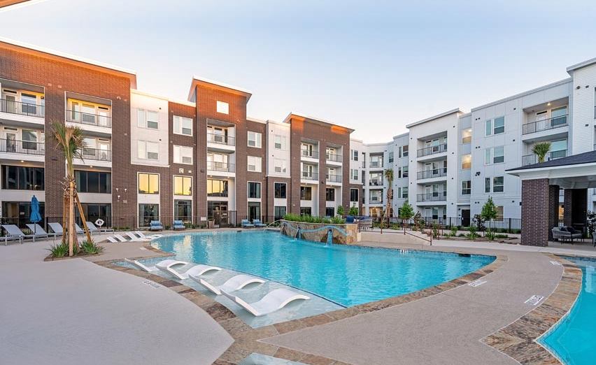 Apartment community pool with shaded seating and a clubhouse deck