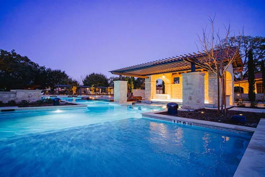 Custom swimming pool and lit outdoor living space at dusk