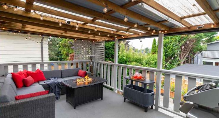 Covered deck with a gas fire table, string lights and outdoor sofas