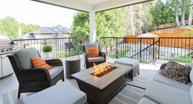 Covered deck with a rectangular fire table and wicker seating