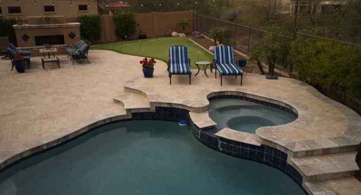 Travertine pool deck with a spa and two lounge chairs