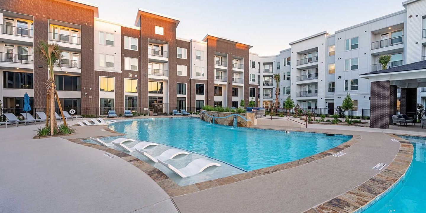 Apartment community pool with lounge chairs and a sun shelf