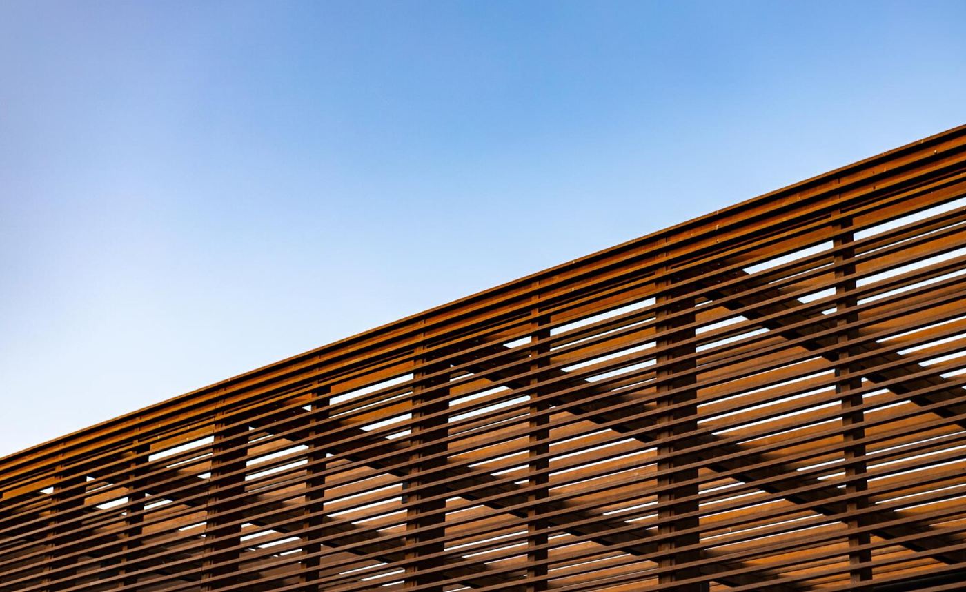 Slatted wooden pergola roof against a clear blue sky