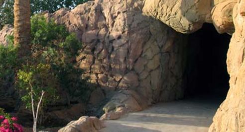 Sculpted rock grotto entrance beside a backyard pool