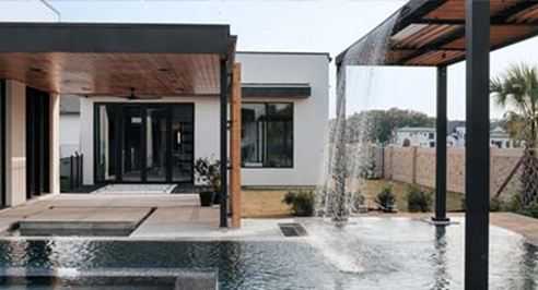 Waterfall pouring into a pool beside a modern covered patio