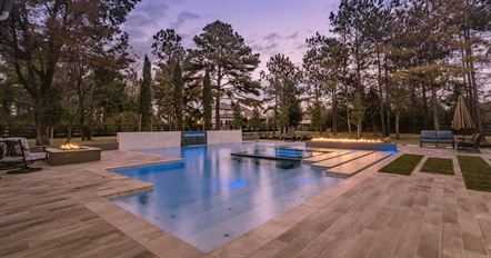 Backyard pool surrounded by trees and a timber deck